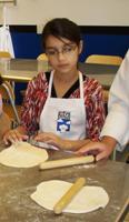 Rolling out pizza dough at A Kid's Kichen